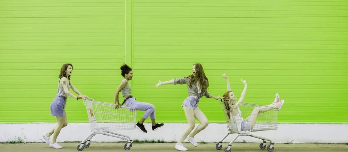 four girls hanging out in empty parking lot having the most fun ever in shopping carts spree spending